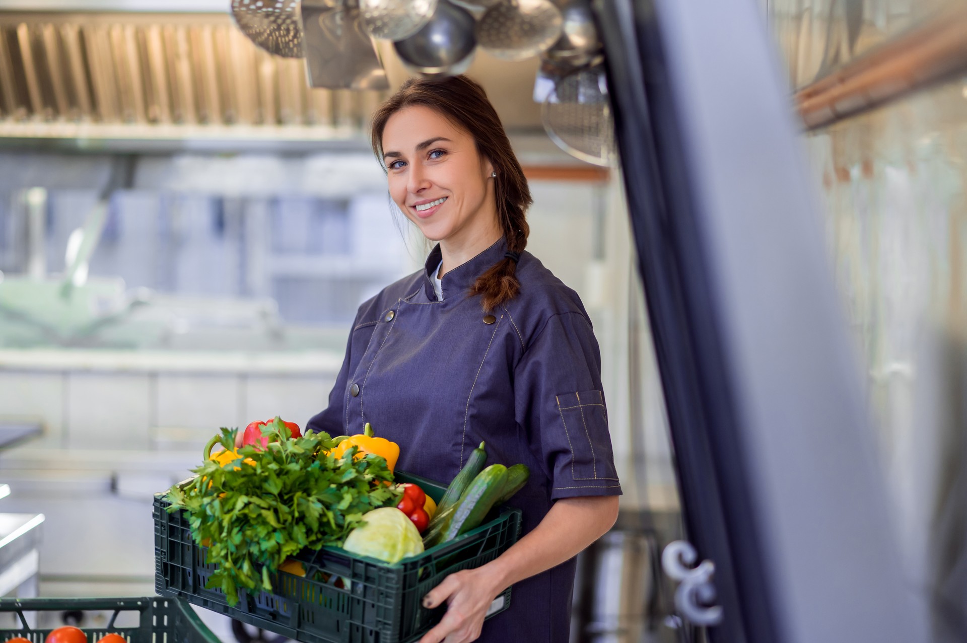 Smiling happy female chef woman holding basket with vegetable